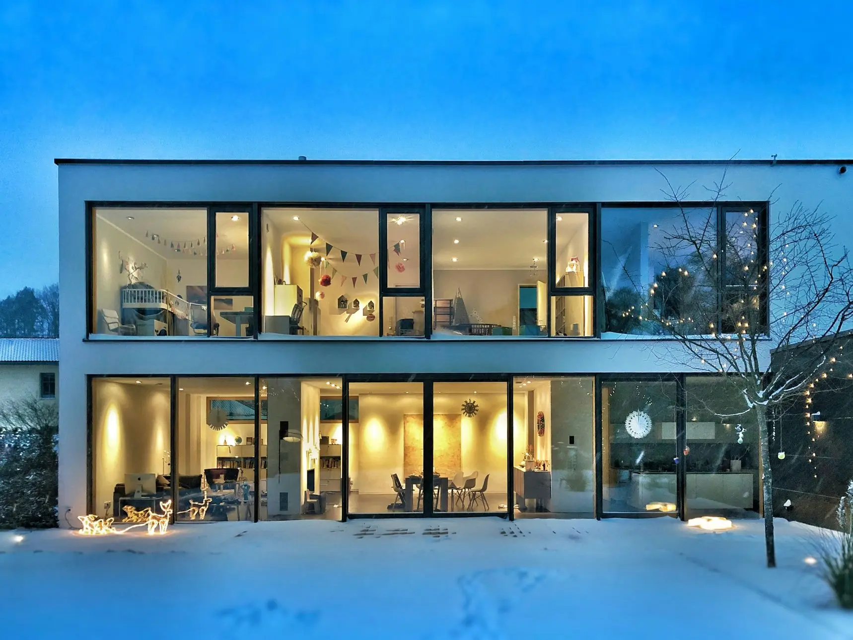 Casa iluminada al atardecer con nieve en el exterior