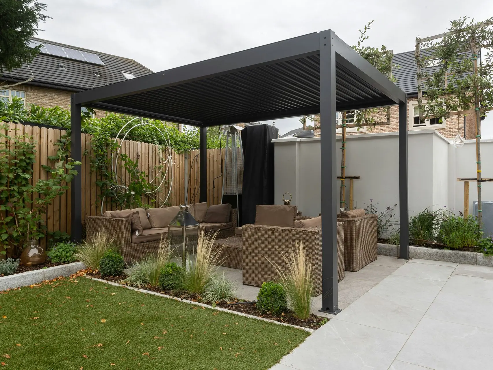 Jardín con pérgola de metal  con sillones debajo