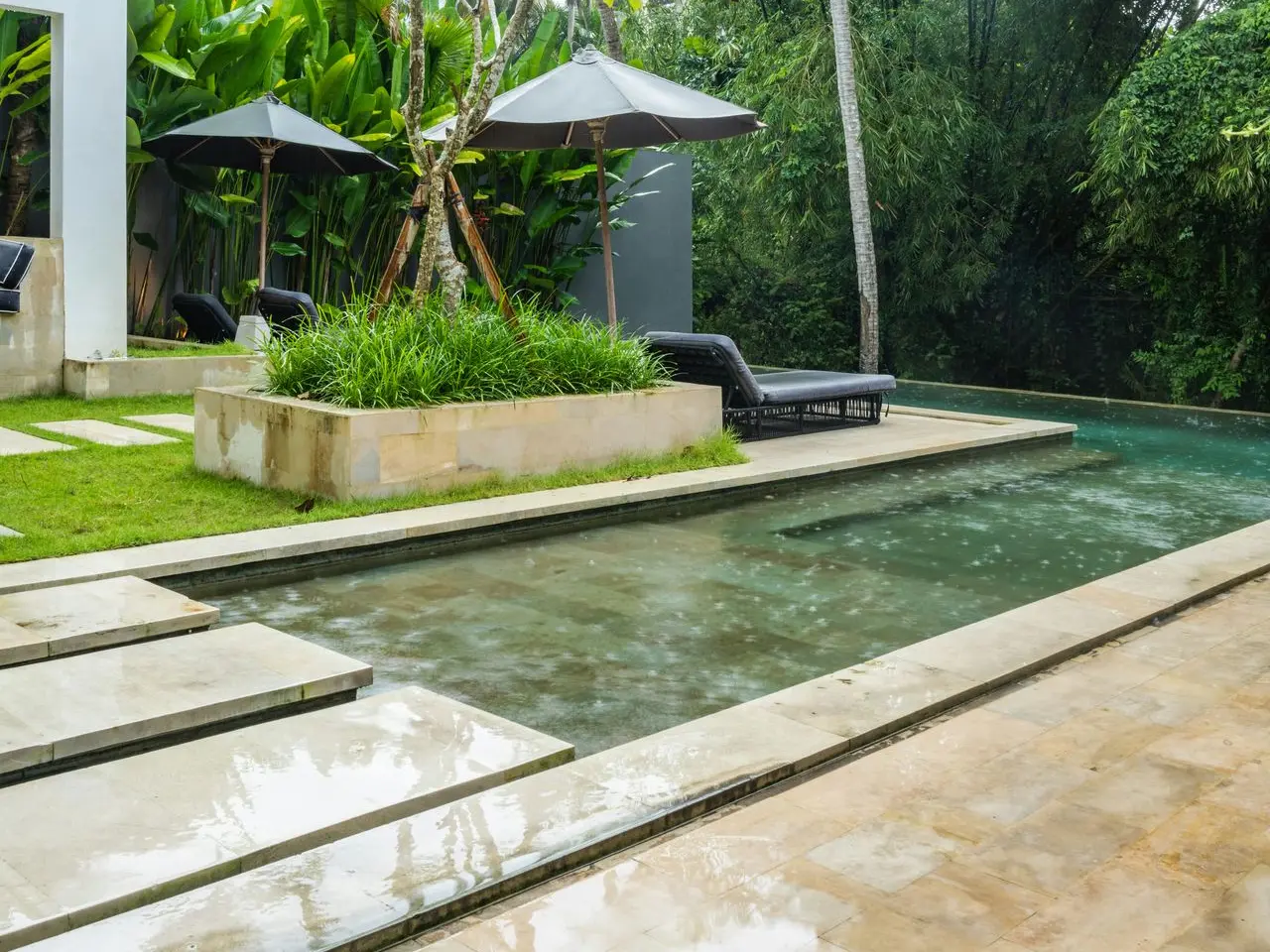 Piscina con hamacas y sombrillas en un jardín